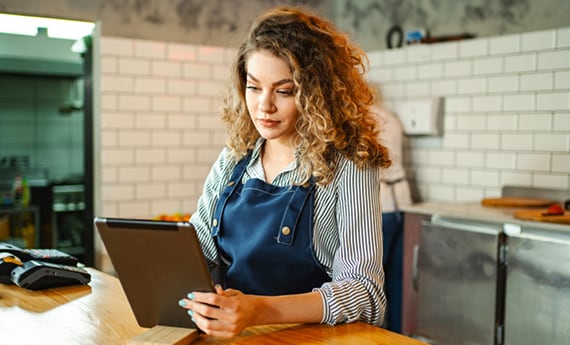 Small business owner standing at counter and holding tablet device