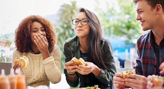 three people enjoying their food
