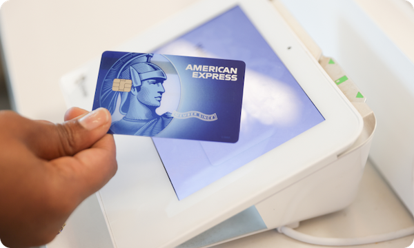 Detail of a woman's hand using an American Express credit card for payment.