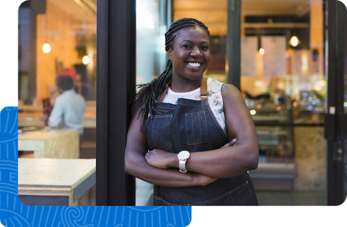 A smiling business owner standing proudly in front of her store.