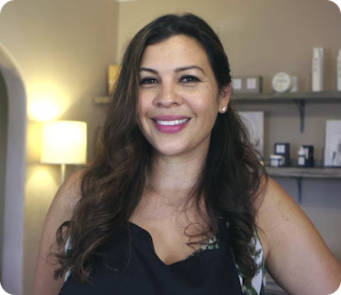 Jenny Ferrera, who is a small business owner, is standing in front of a supply of skincare.